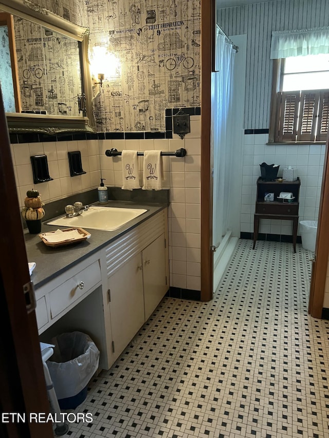 full bath with wallpapered walls, vanity, tile walls, and a stall shower