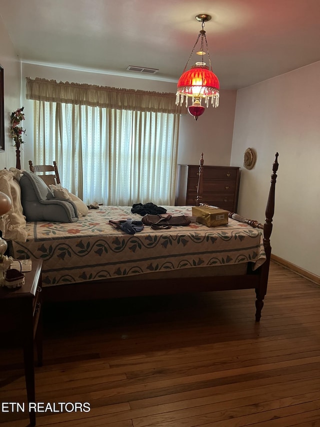 bedroom with visible vents, baseboards, and wood finished floors