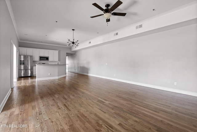 unfurnished living room featuring dark wood-style floors, baseboards, visible vents, ornamental molding, and ceiling fan with notable chandelier