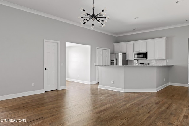 kitchen featuring tasteful backsplash, ornamental molding, an inviting chandelier, stainless steel appliances, and dark wood-style flooring