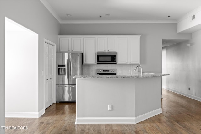 kitchen featuring decorative backsplash, white cabinets, stainless steel appliances, and wood finished floors