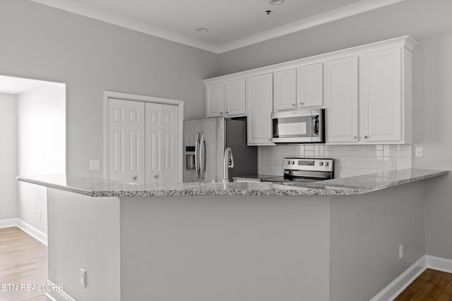 kitchen featuring stainless steel appliances, tasteful backsplash, wood finished floors, and white cabinetry