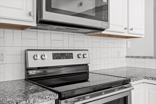 kitchen featuring backsplash, appliances with stainless steel finishes, white cabinetry, and light stone countertops