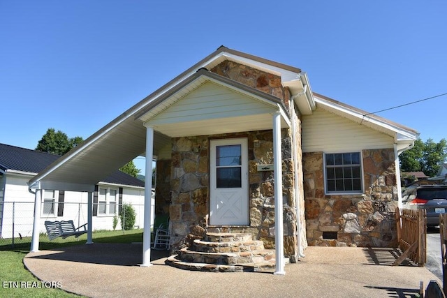 view of front facade featuring entry steps, fence, and stone siding