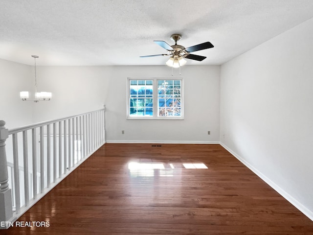 empty room with a textured ceiling, baseboards, and wood finished floors