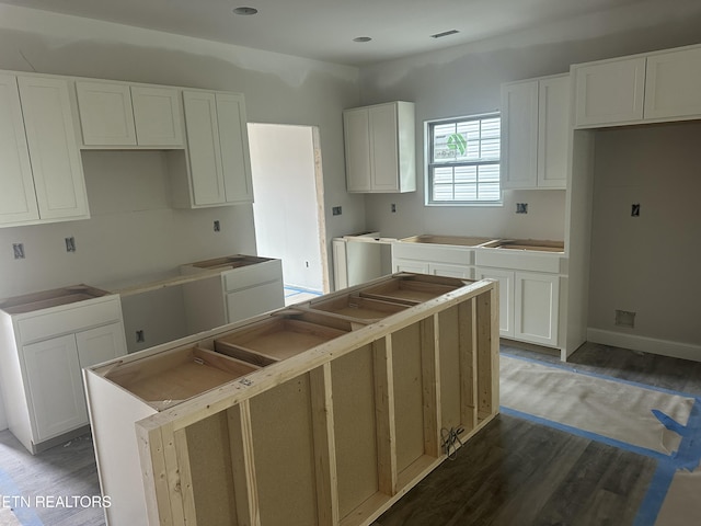 kitchen featuring white cabinets, a kitchen island, baseboards, and wood finished floors