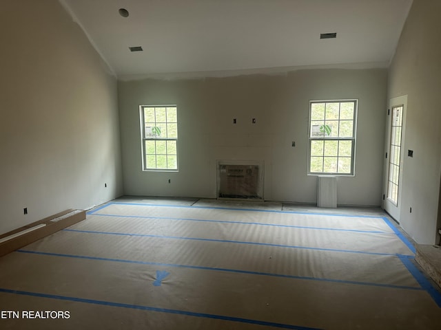 unfurnished living room with a wealth of natural light, visible vents, and lofted ceiling