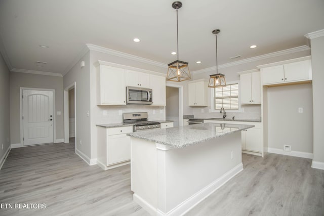 kitchen with white cabinets, a center island, appliances with stainless steel finishes, and light wood finished floors