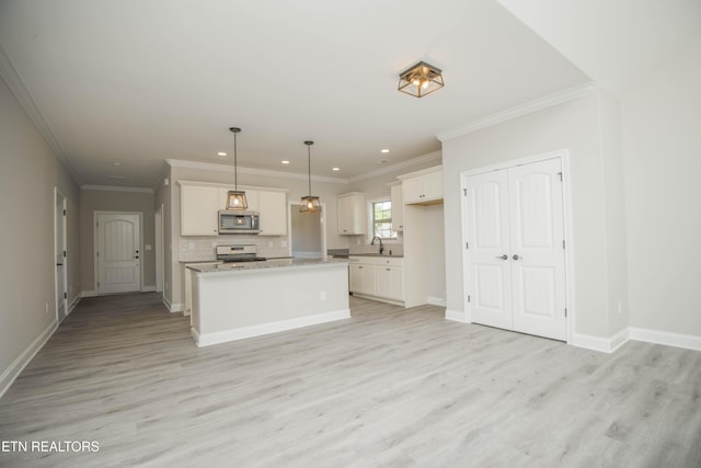 kitchen featuring decorative backsplash, appliances with stainless steel finishes, white cabinetry, a sink, and light wood-type flooring