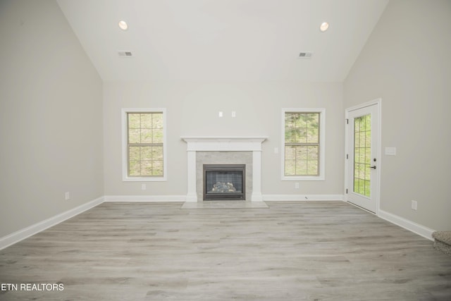 unfurnished living room featuring a fireplace with flush hearth, high vaulted ceiling, visible vents, and wood finished floors