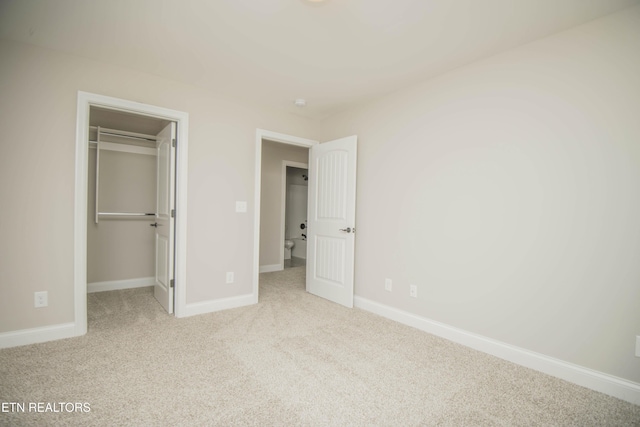 unfurnished bedroom with baseboards, carpet flooring, a closet, and a walk in closet