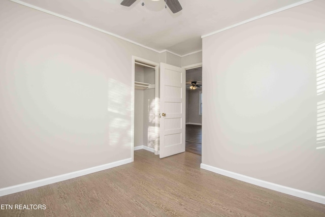 unfurnished bedroom with baseboards, a closet, wood finished floors, and crown molding