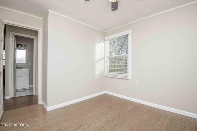 empty room featuring ornamental molding, wood finished floors, and baseboards