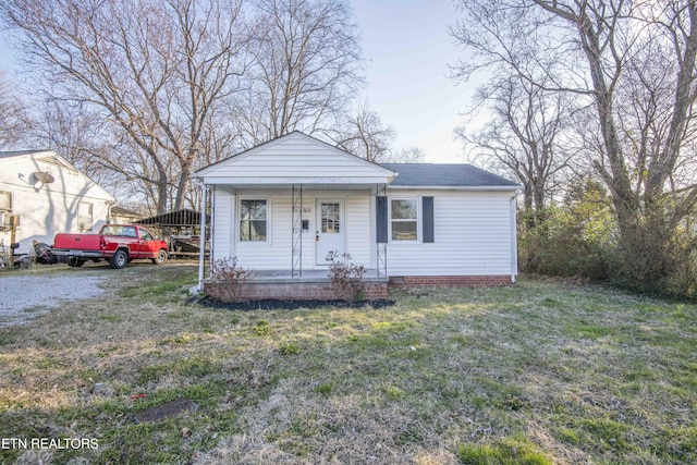 view of front of home with covered porch, a shingled roof, and a front yard