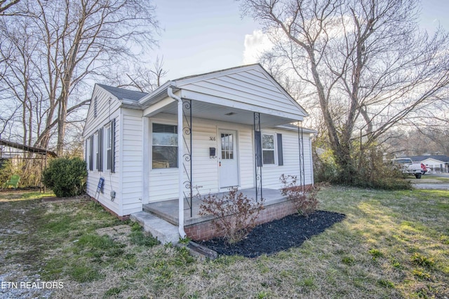 bungalow-style house featuring covered porch and a front lawn