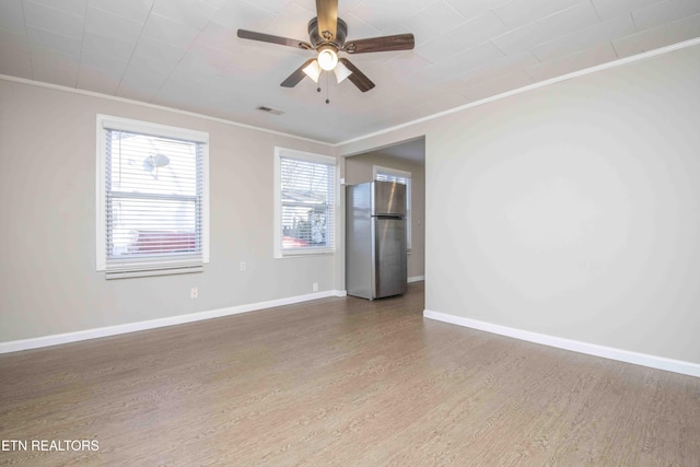 unfurnished room with ornamental molding, a ceiling fan, baseboards, and wood finished floors