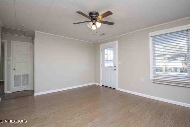 interior space with baseboards, crown molding, visible vents, and wood finished floors