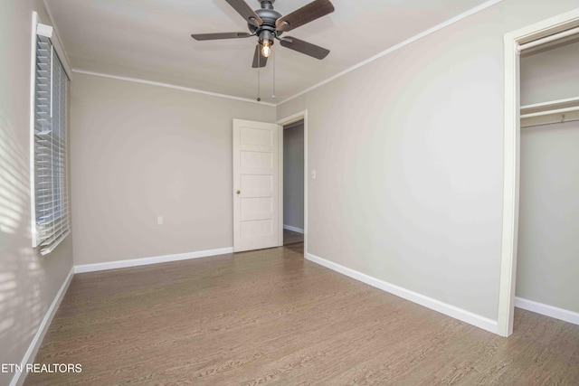 unfurnished bedroom featuring baseboards, a closet, ornamental molding, and wood finished floors