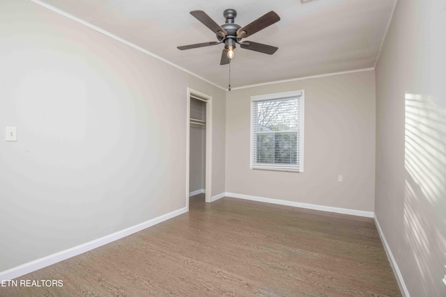 unfurnished bedroom featuring a closet, crown molding, baseboards, and wood finished floors