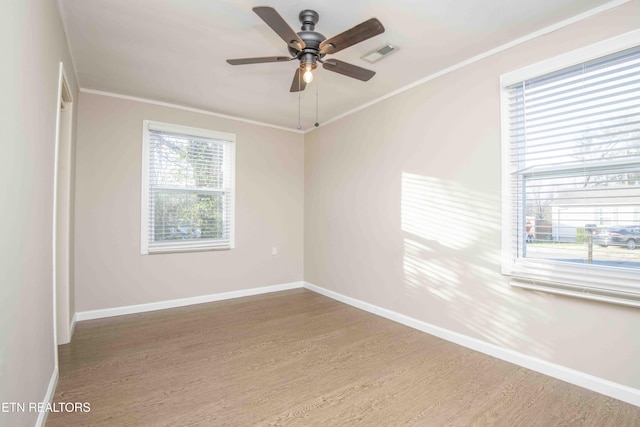 empty room featuring baseboards, visible vents, ceiling fan, ornamental molding, and wood finished floors