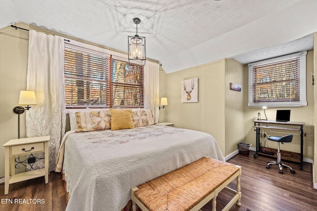 bedroom with baseboards, a textured ceiling, lofted ceiling, and wood finished floors