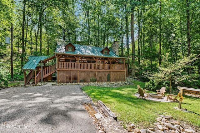 back of property featuring a standing seam roof, a yard, a fire pit, metal roof, and stairs
