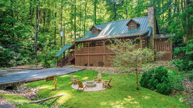 back of property featuring a standing seam roof, a fire pit, a wooded view, metal roof, and stairs