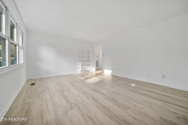unfurnished living room featuring light wood-type flooring, visible vents, and baseboards