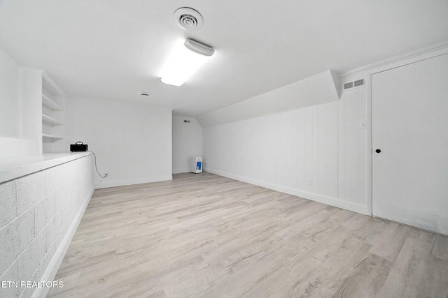 bonus room featuring light wood-type flooring, visible vents, built in features, and vaulted ceiling