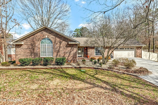 single story home featuring a garage, a front yard, concrete driveway, and brick siding