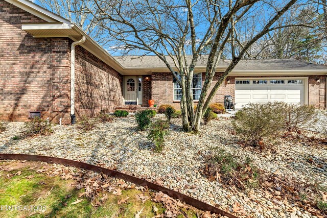 view of front of property with a garage, brick siding, and crawl space