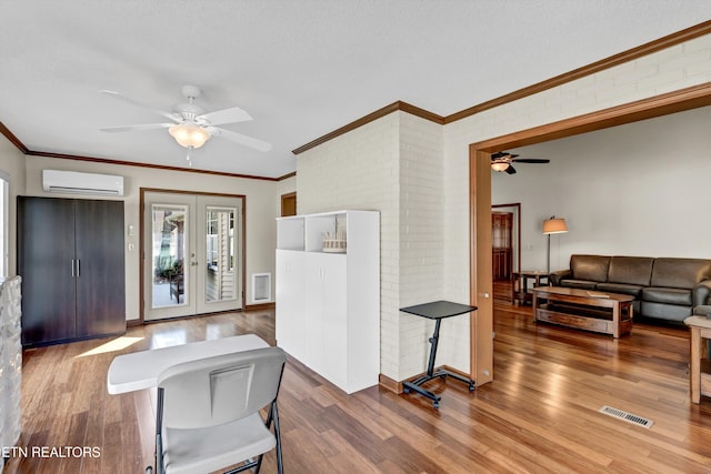 interior space with french doors, visible vents, an AC wall unit, brick wall, and wood finished floors