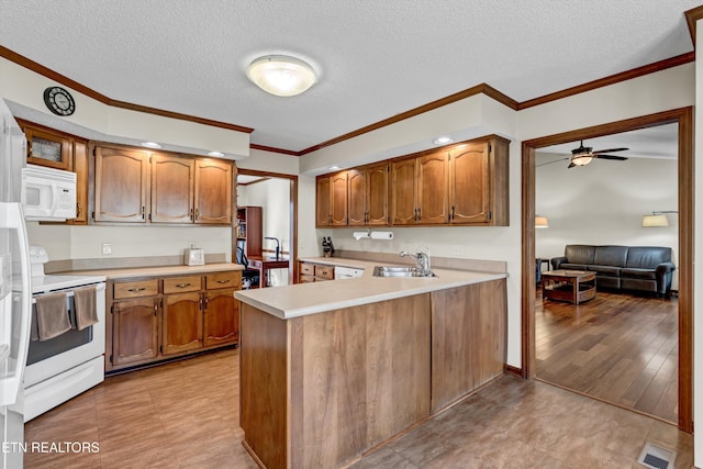 kitchen with light countertops, visible vents, a sink, white appliances, and a peninsula