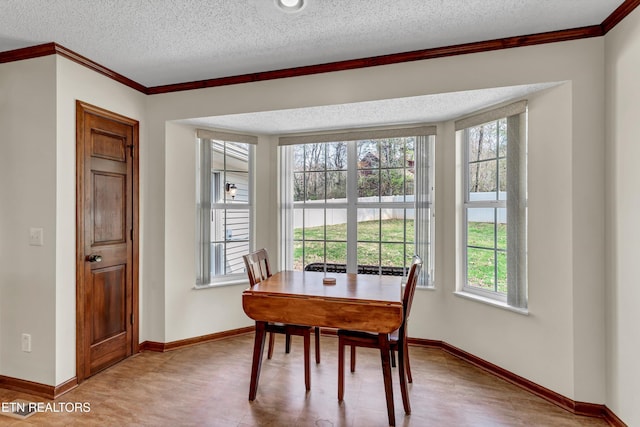 dining space with ornamental molding, a textured ceiling, and baseboards