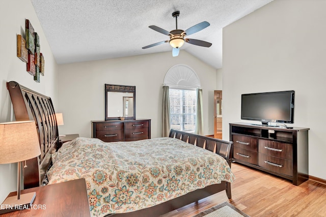 bedroom featuring lofted ceiling, light wood-style flooring, ceiling fan, and a textured ceiling