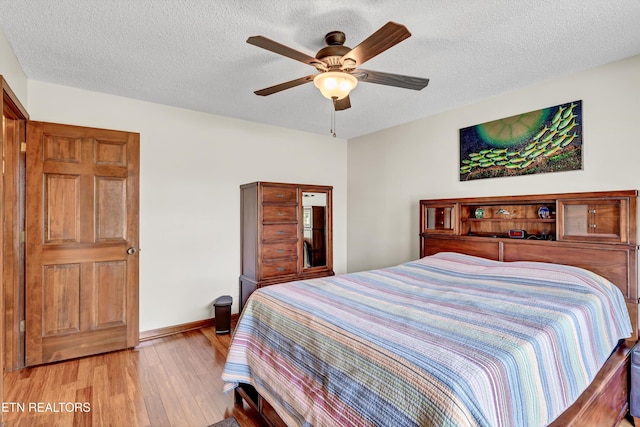 bedroom featuring light wood-style floors, a textured ceiling, baseboards, and a ceiling fan