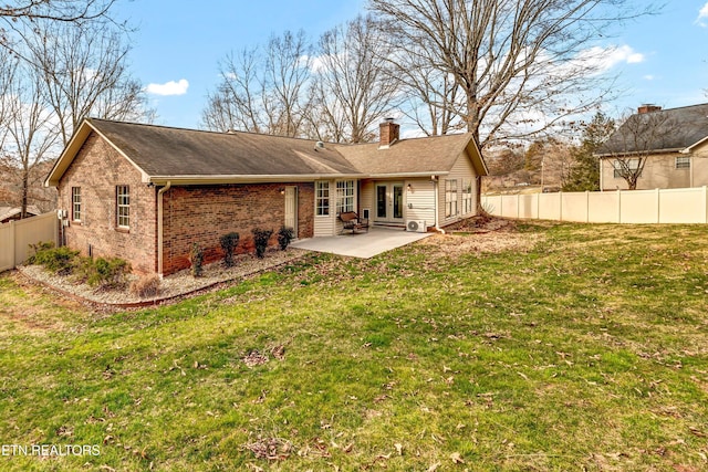 back of house with a patio, brick siding, fence, french doors, and a lawn