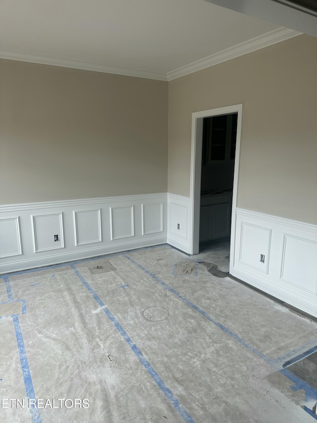 spare room with a wainscoted wall and ornamental molding