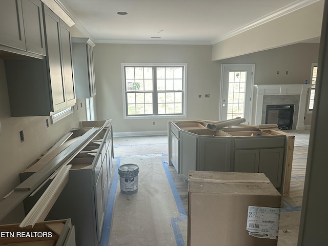 kitchen featuring a glass covered fireplace, a kitchen island, baseboards, and ornamental molding