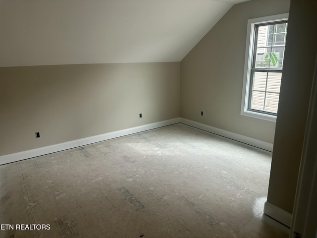 additional living space with baseboards and vaulted ceiling