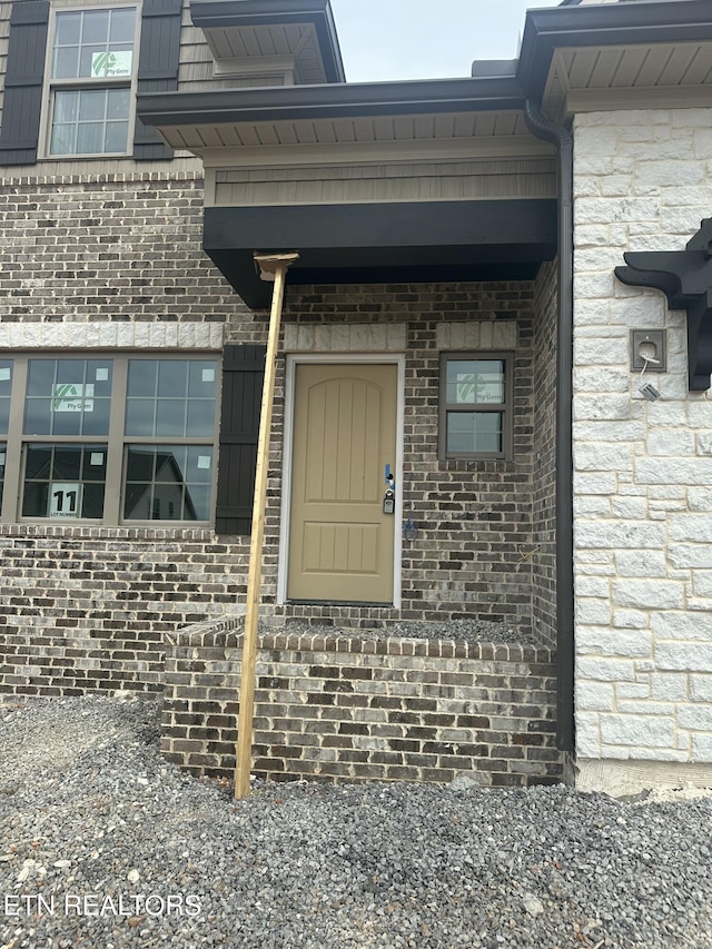 view of exterior entry featuring brick siding and stone siding