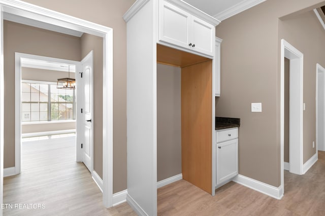 corridor with an inviting chandelier, baseboards, and light wood finished floors