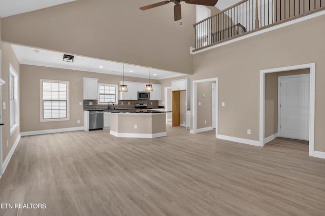 unfurnished living room featuring baseboards, light wood-style floors, ceiling fan, and ornamental molding