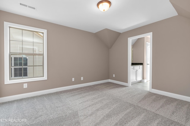 additional living space with light colored carpet, visible vents, baseboards, and vaulted ceiling