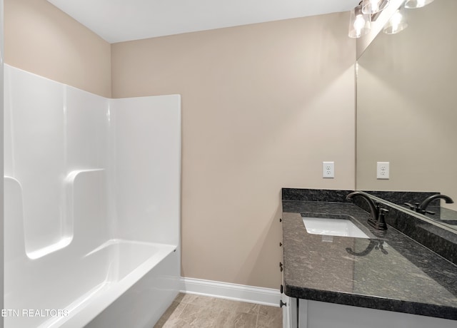 bathroom featuring vanity, baseboards, and bathing tub / shower combination