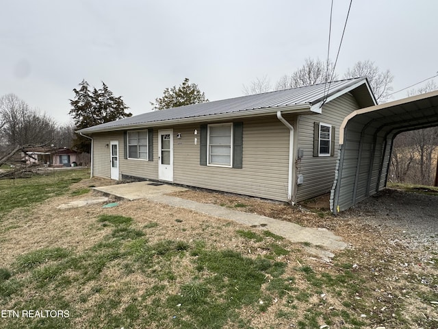 single story home with metal roof, a front yard, and a detached carport