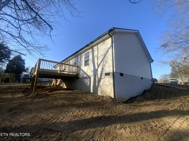 view of side of property with crawl space, a wooden deck, and stairs