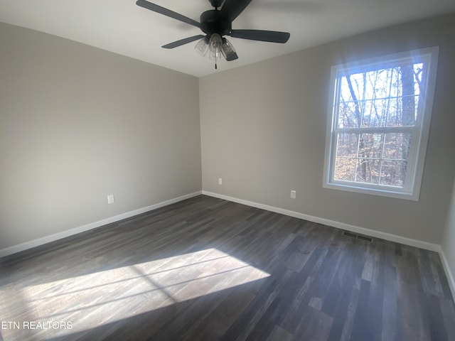 empty room with dark wood-type flooring, visible vents, baseboards, and ceiling fan