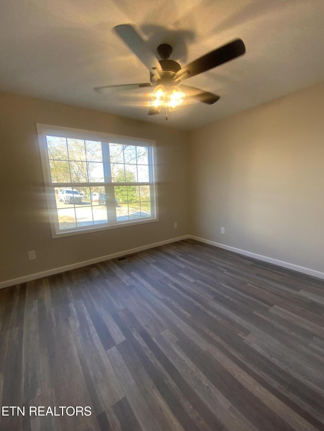 empty room with dark wood finished floors, baseboards, and ceiling fan