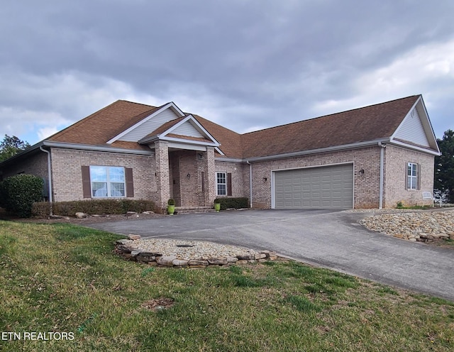 view of front of house with a front yard, brick siding, driveway, and an attached garage